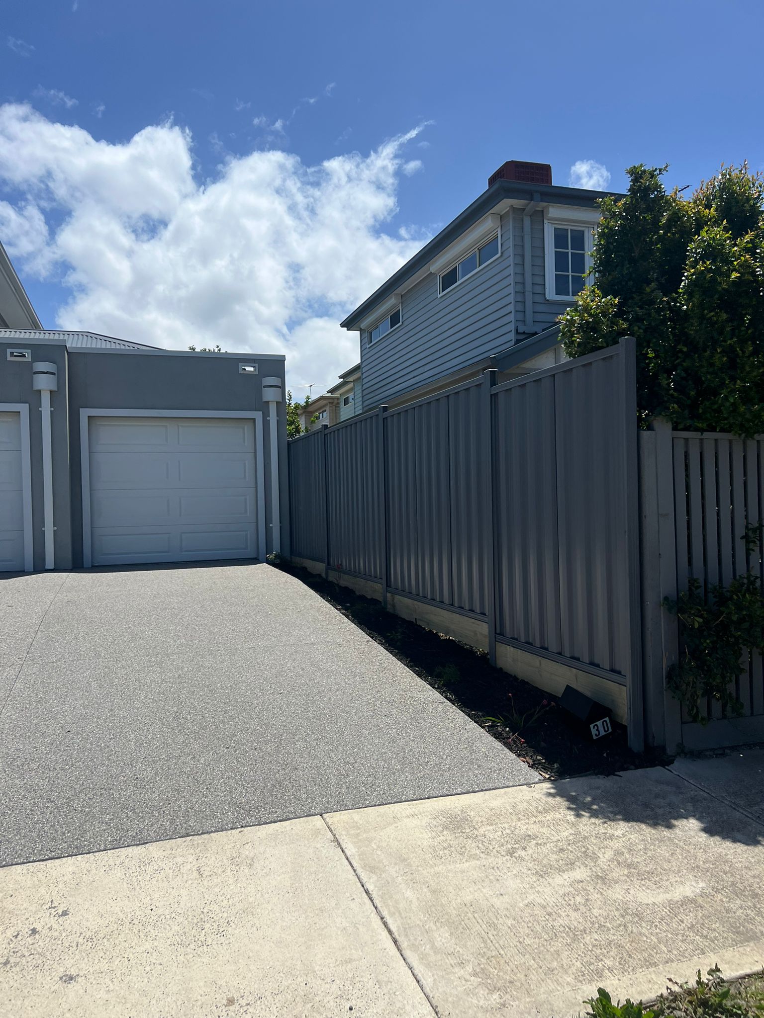Commercial-grade grey Colorbond fence along a driveway